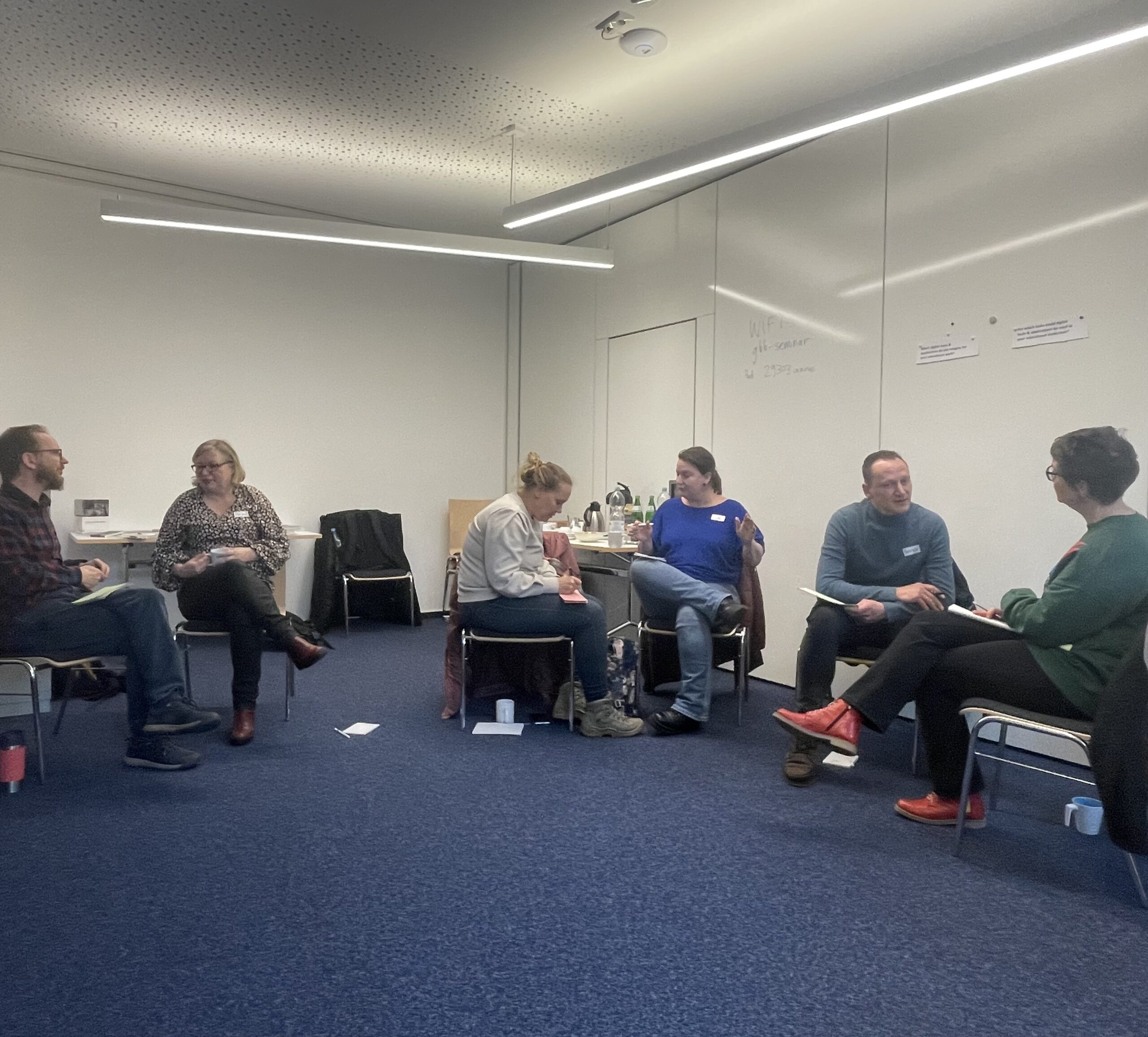 Educators sitting in a seminar room discussing digital education in groups.